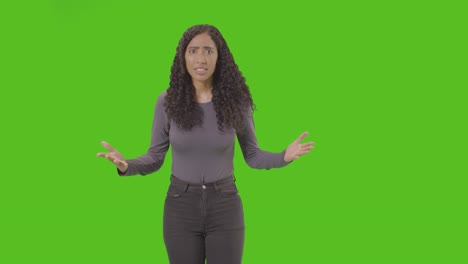 three quarter length shot of angry looking woman shouting at camera against green screen