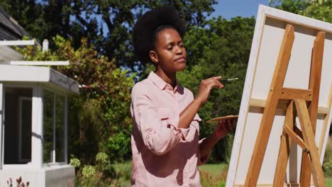 Mujer-Afroamericana-Pintando-Un-Cuadro-Sobre-Lienzo-En-Un-Jardín-Soleado