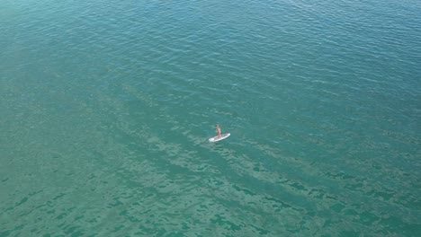 A-woman-stands-and-paddles-over-small-waves-on-a-SUP-in-the-Aegean-Sea-near-Paros-island-in-Greece