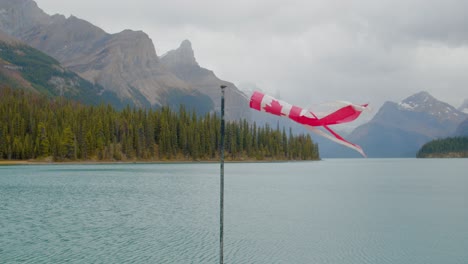 Bandera-Canadiense-Despertando-Con-El-Viento-Cerca-De-Un-Impresionante-Lago-De-Agua-Verde-Rodeado-De-Altas-Montañas-En-Las-Montañas-Rocosas-Canadienses