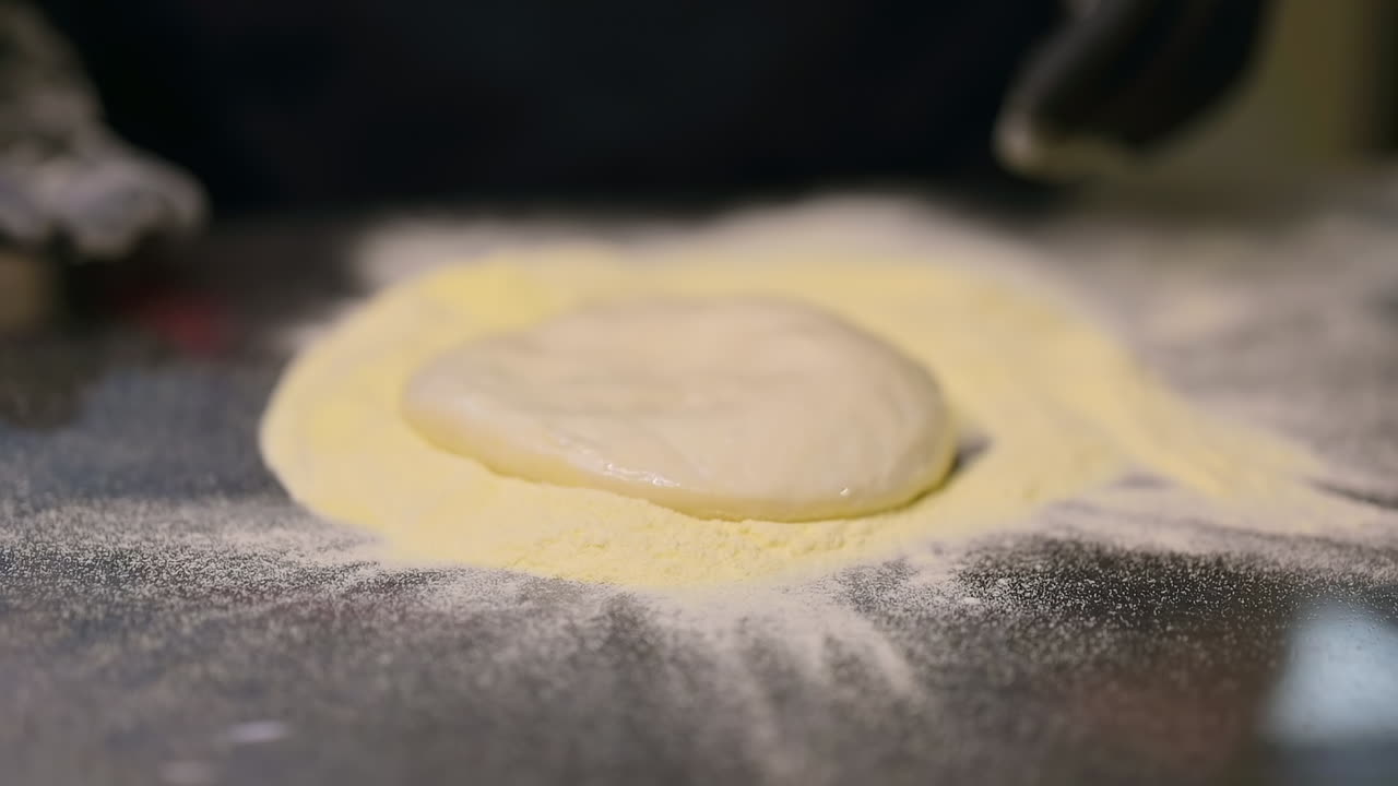 Chef rolling out pizza dough. Italian pizza chef forming the dough on a floured surface