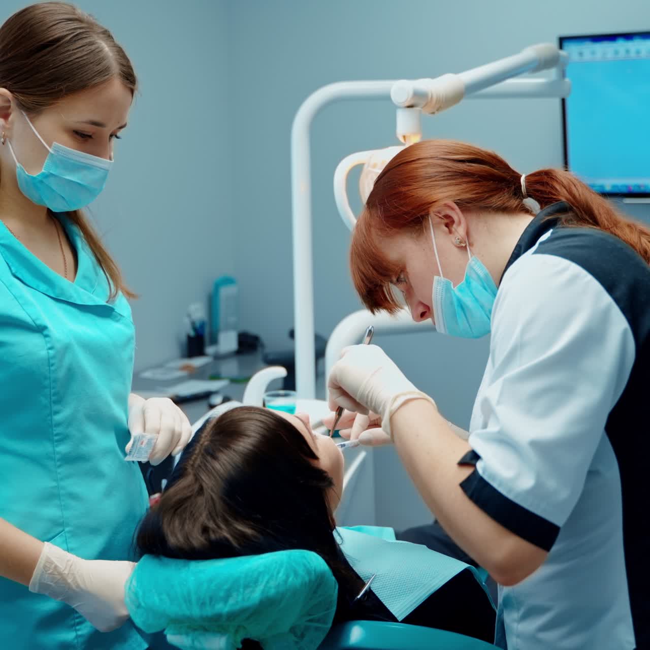 Dentist with assistant treat patient's teeth. Dental procedure in the modern stomatology office. Female dentist working in patient oral cavity.