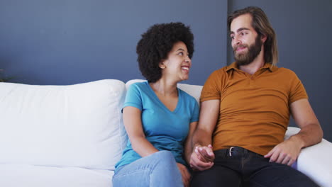 portrait of mixed race couple holding hands while sitting on the couch at home