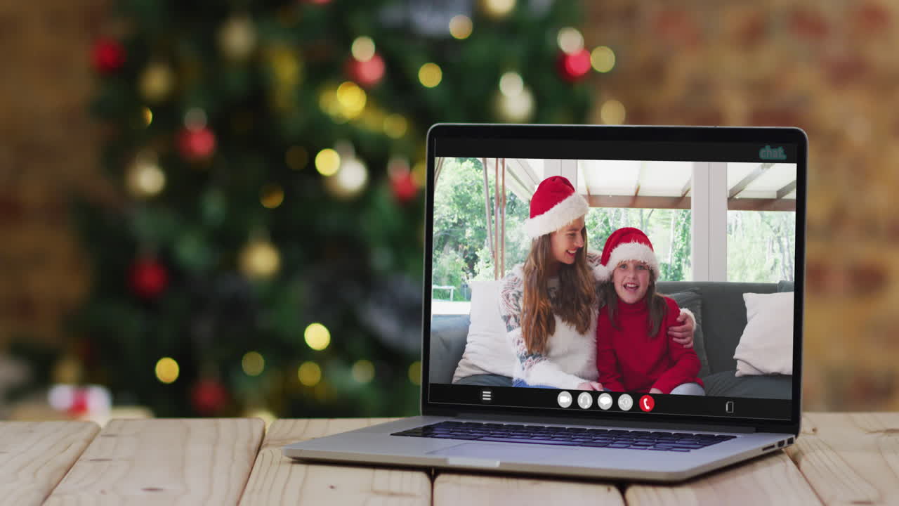 madre y hija felices en videollamada en computadora portátil, con decoraciones de navidad y árbol