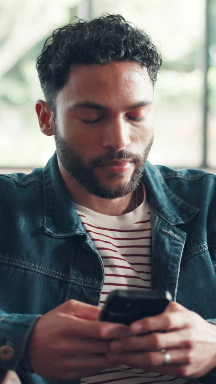 Giovane sorridente mentre usa lo smartphone in casa
