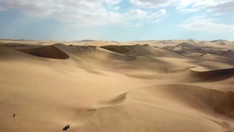 aérea, toma de drones, con vista a un buggy todoterreno y dunas de arena, en el desierto de atacama, en un día soleado, en el suroeste de perú