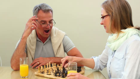 una pareja madura jugando al ajedrez juntos en la mesa.