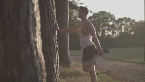 Hombre-En-El-Parque-Estirando-Las-Piernas-Antes-De-Salir-A-Correr-Mientras-El-Sol-Se-Pone-Detrás-De-él-En-Cámara-Lenta---Sin-Clasificar