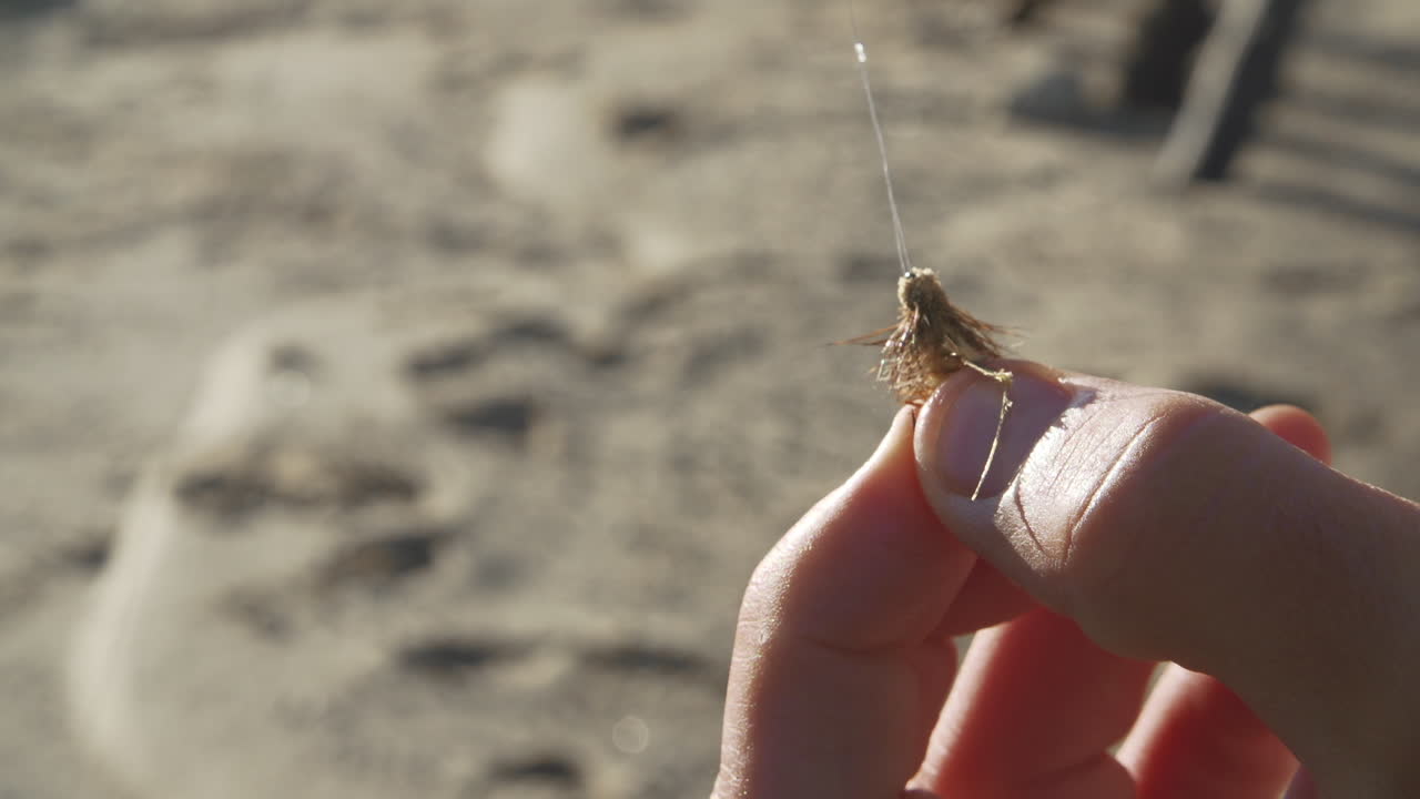 제물 낚시 미끼 주위에 매듭을 조이는 남성 어부의 손을 닫습니다