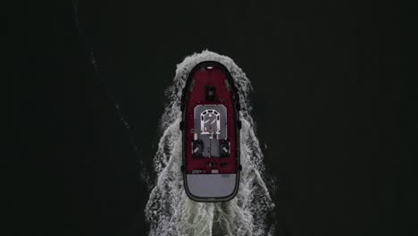 an aerial view high above a lone tugboat on a cloudy morning in the hudson river, near brooklyn, ny