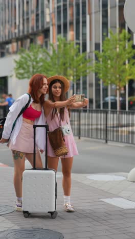 two women taking a selfie with luggage in the city