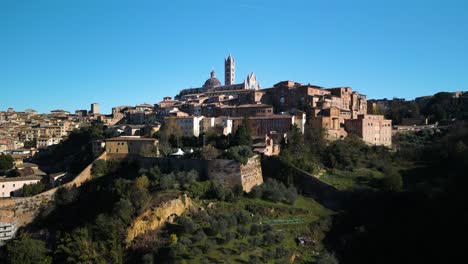 aerial boom shot reveals siena city on hilltop in tuscany, italy