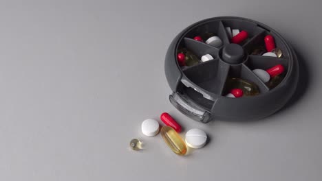 zoom in of plastic container with pills and capsules inside on table surface