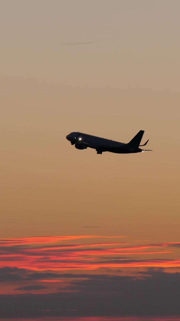 Sort silhuet af flyvende fly på aftenhimlen