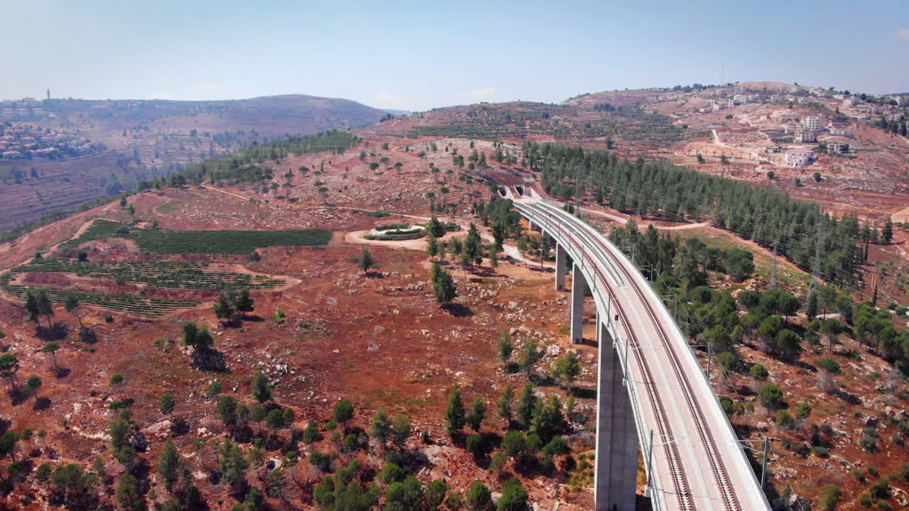 Aerial footage of Modern passenger train crossing a bridge and entering tunnel