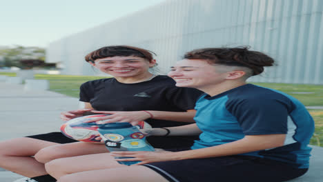 two female soccer players drinking water and chatting after outdoor training