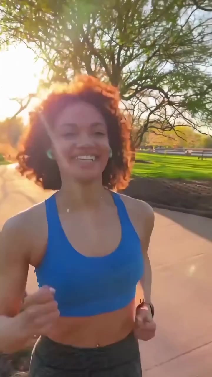 Giovane donna felice che fa jogging in un parco soleggiato