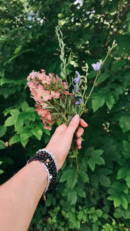 hand holding a bouquet of flowers in nature