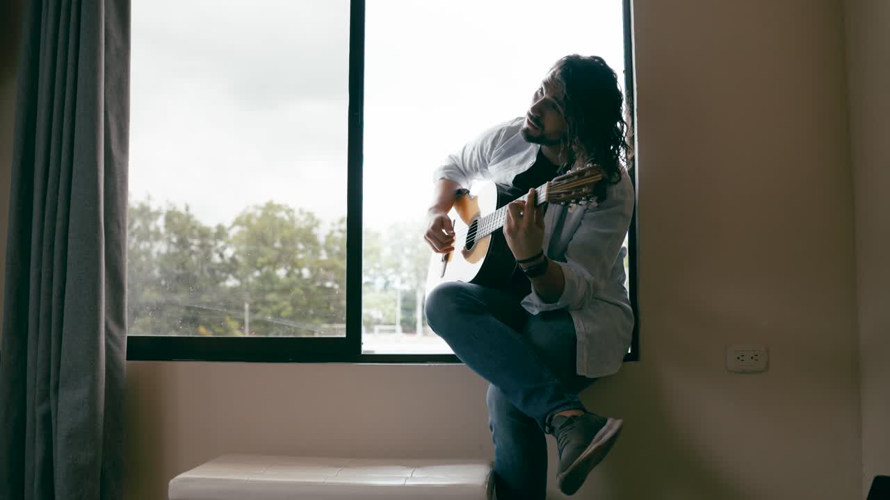 hombre tocando la guitarra junto a la ventana
