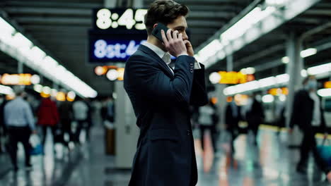 businessman talking on phone at train station