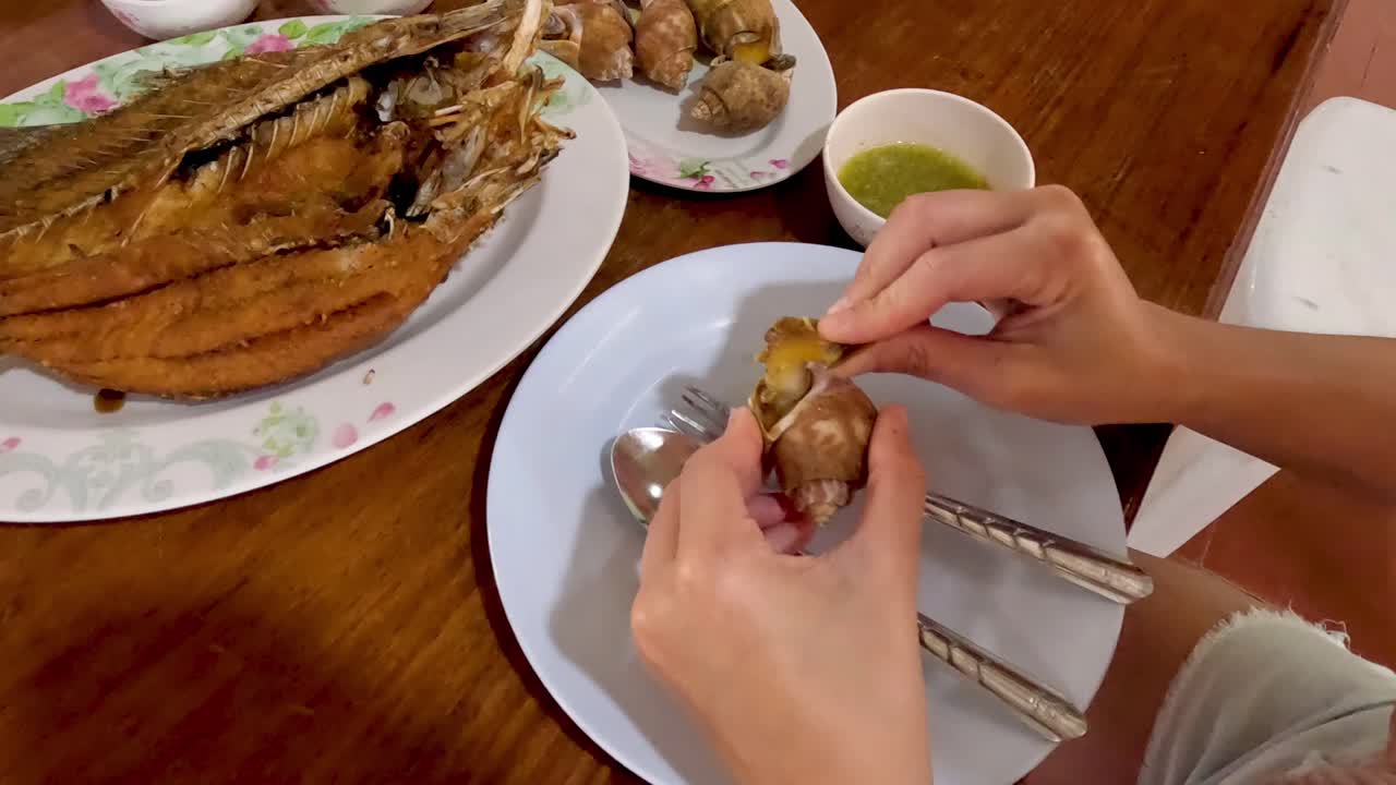 Person eating fish and dipping sauce at table.