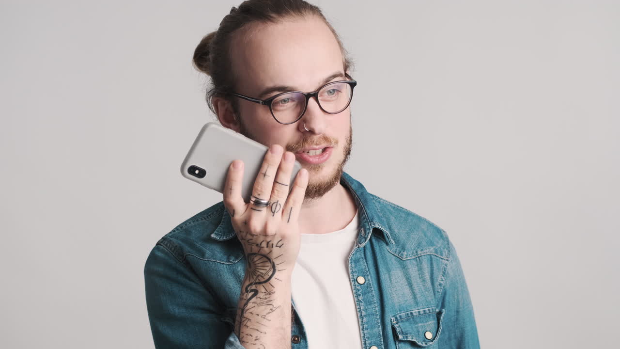 Caucasian young man recording voice message on smartphone.