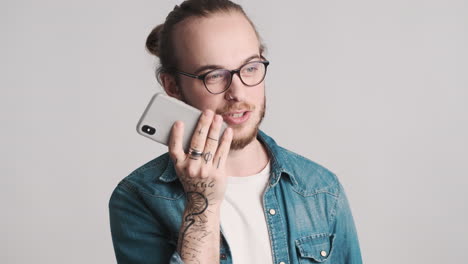 caucasian young man recording voice message on smartphone.