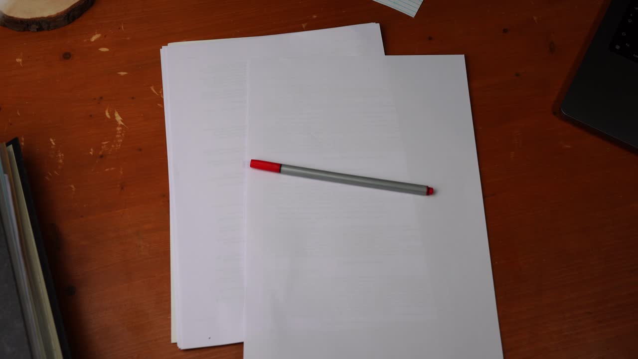 Red pen for marking mistakes is placed on a desk and writes off again