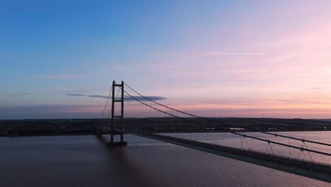 Humber-Bridge-bathed-in-sunset's-warmth,-cars-traverse-its-span