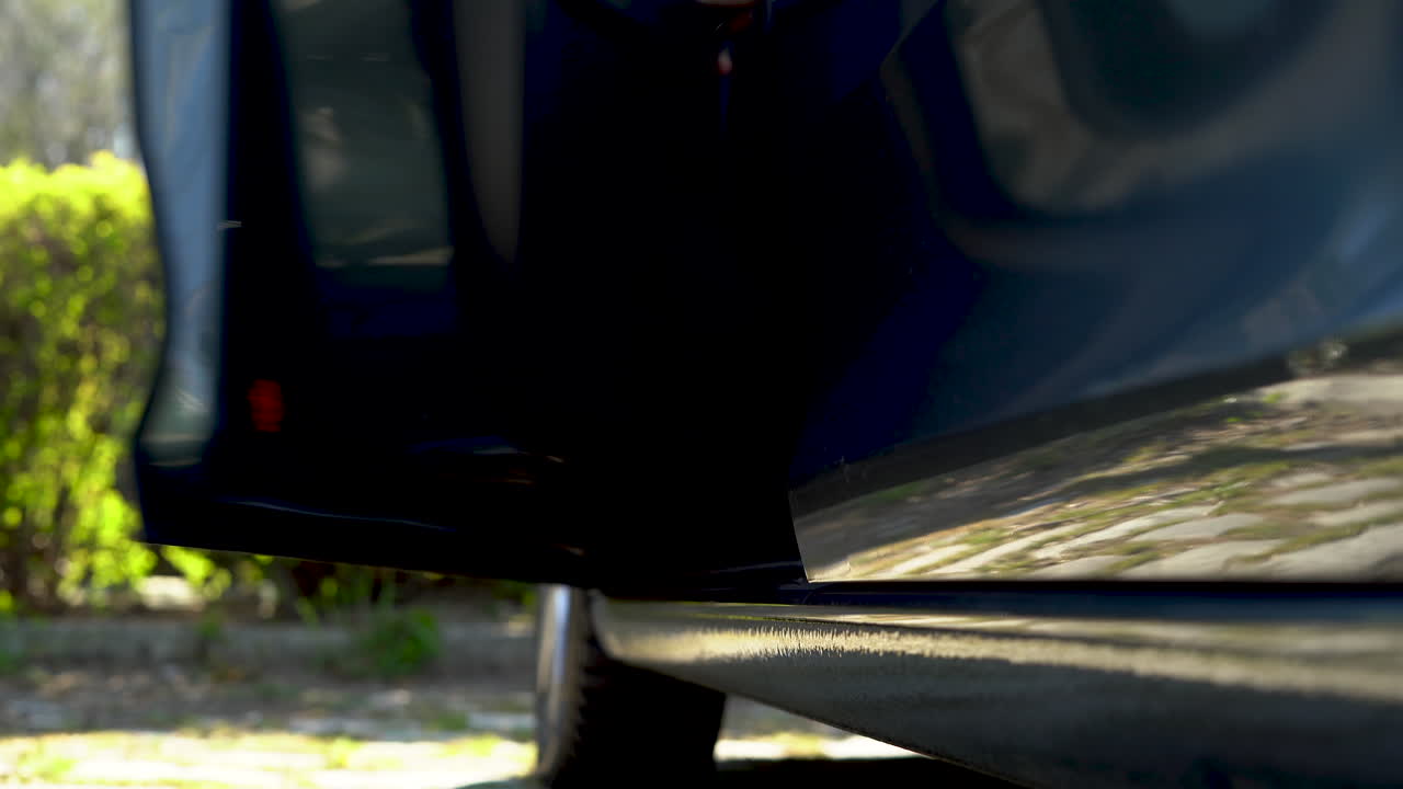 남자가 차 문을 열고, 차에 들어가서 문을 닫습니다. 낮은 각도입니다.