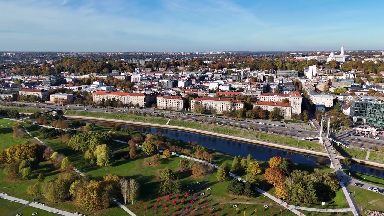 Panorama Kowna, ukazująca rzekę Niemen wijącą się przez centrum miasta, most Simonasa Daukantasa oraz jesienne listowie zdobiące parki wzdłuż jej brzegów, Litwa, ujęcie z drona.