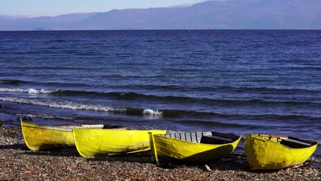 barcos de pesca amarillos en la orilla del lago ondulante con agua azul en el hermoso amanecer en la mañana de otoño