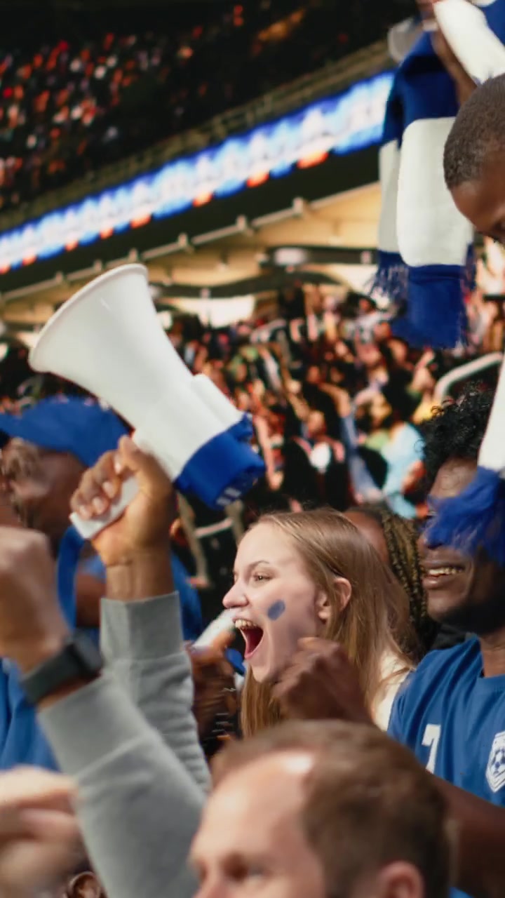 Video vertical de un niño aficionado celebrando con hinchas de fútbol azules animando en el estadio