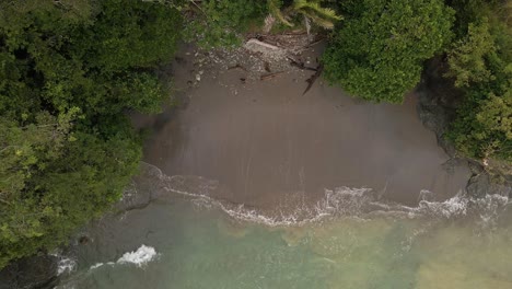 top down view rising drone flight over a sandy beach of a tropical island in the ocean