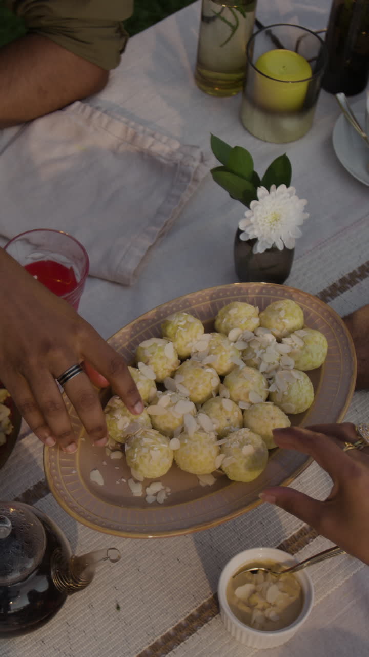 Hands reaching for shared almond-topped desserts at a gathering