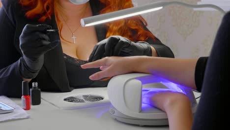 la mujer roja hace un procedimiento de spa para las uñas del cliente