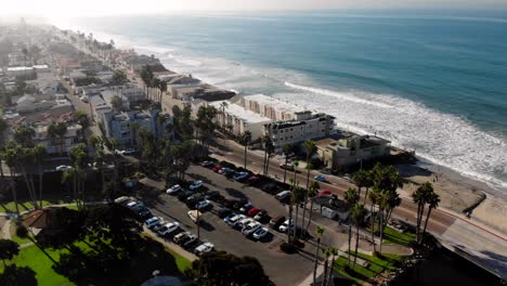 Aerial-pan-of-expensive-homes-overlooking-a-beach-with-crashing-waves