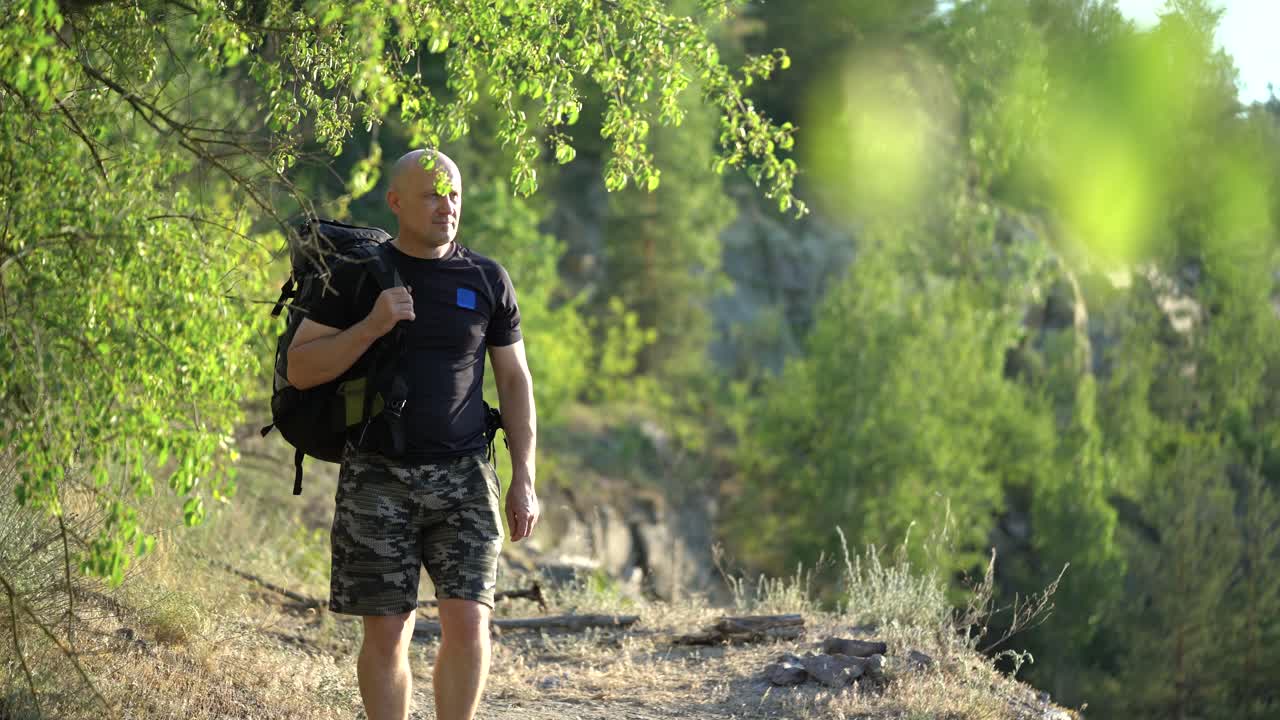 Aerial view of a young traveler with a backpack walking along a rocky path. Camping season. Travel concept.