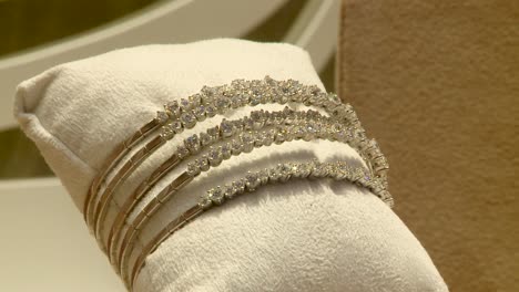 gold and diamond bracelets on a display pillow