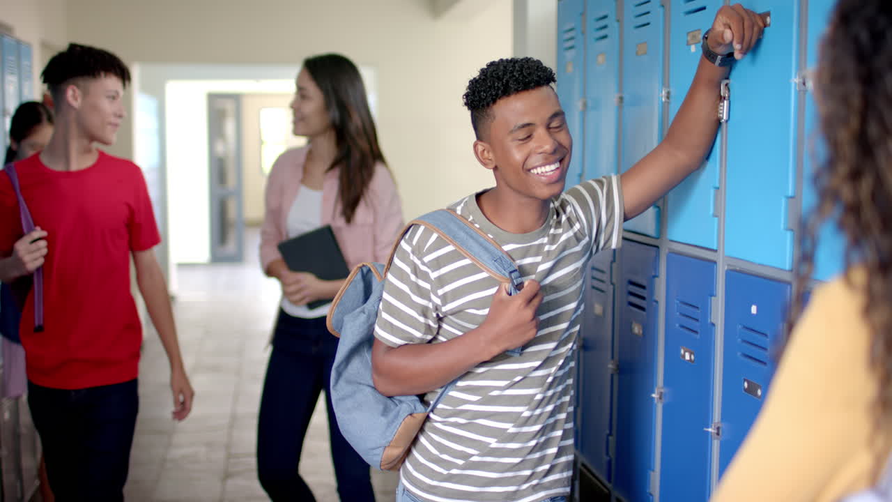 Biracial teenage boy with a bright smile opens his locker at school in high school