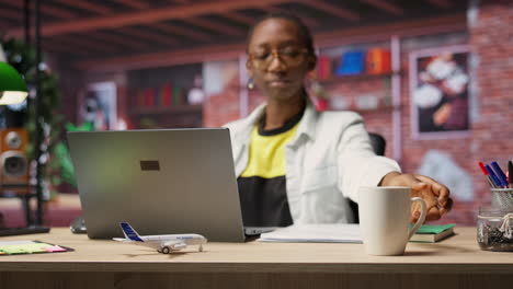 woman drinking coffee at home while looking at social media on laptop