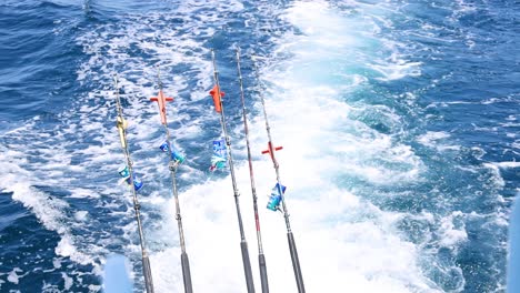 fishing rods on a boat in phuket, thailand, cutting through vibrant blue waters under bright sunlight, capturing a serene marine journey