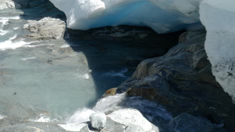 glacial runoff flows under massive chunks of glacier ice