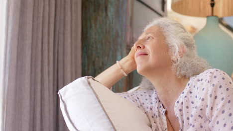 caucasian senior woman with gray hair relaxing, holding pillow, copy space