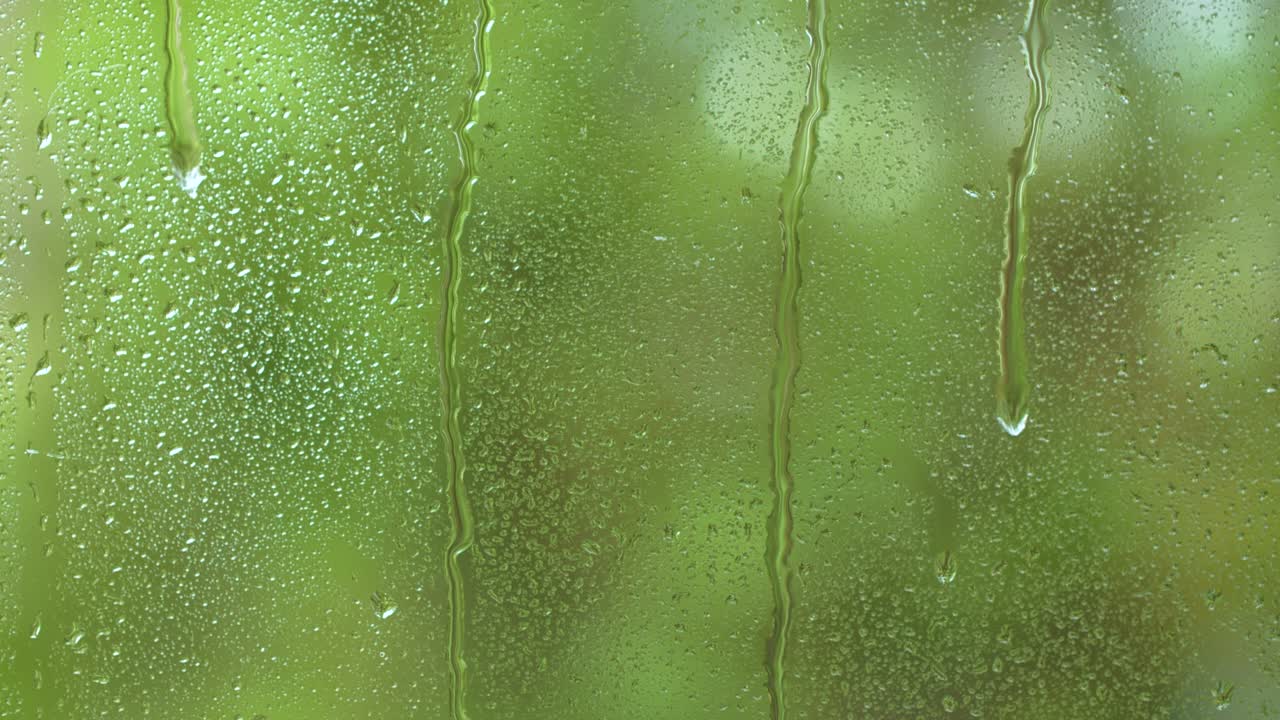 naturaleza lluvia de agua, gotas de lluvia textura en el vidrio de la ventana, árboles verdes borrosos