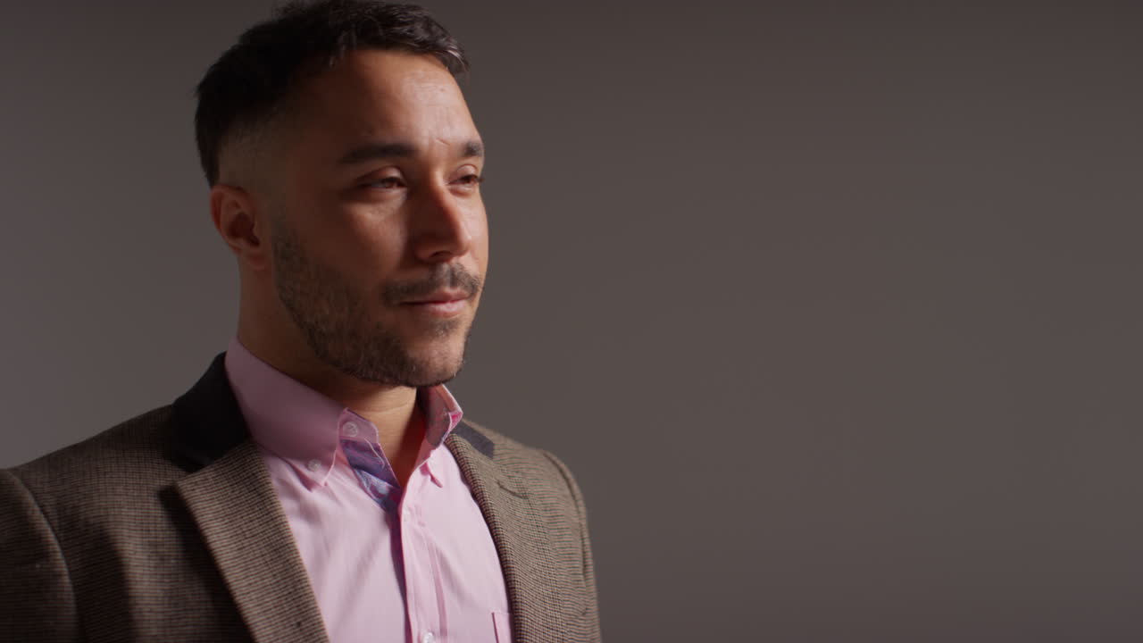 retrato de estudio de un maestro de sexo masculino maduro sonriente con chaqueta de pie contra un fondo gris disparado en cámara lenta