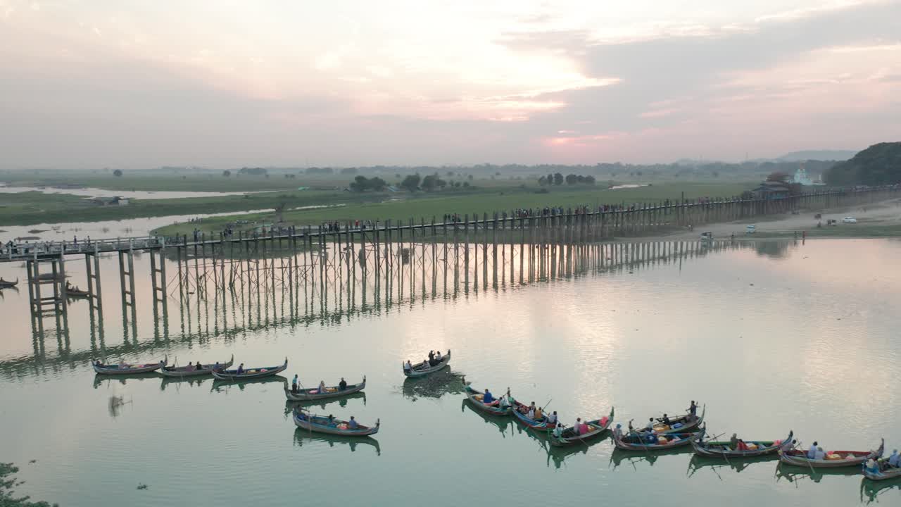 Paesaggio al tramonto al ponte U-Bein con barche da pesca tradizionali nel fiume.