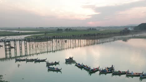 sunset scenery at u-bein bridge with traditional fishing boats in river