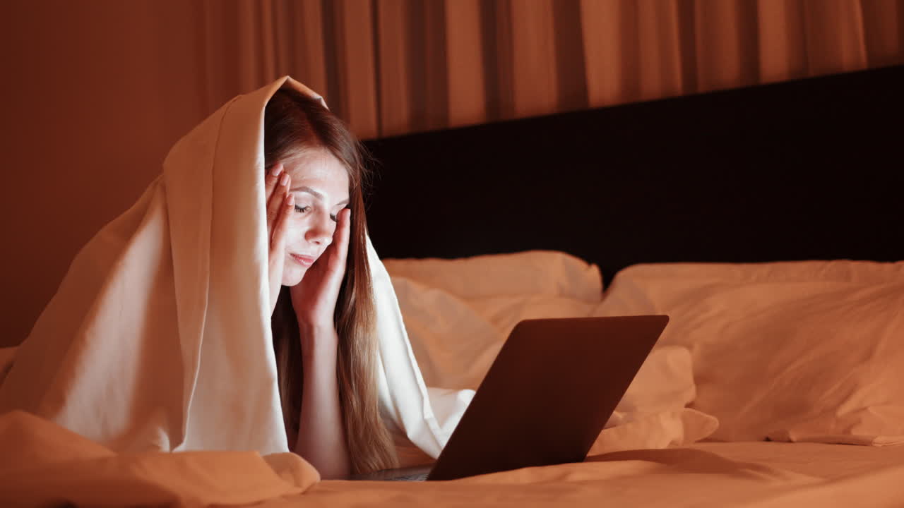 밤에 침대에서 노트북으로 일하는 여자