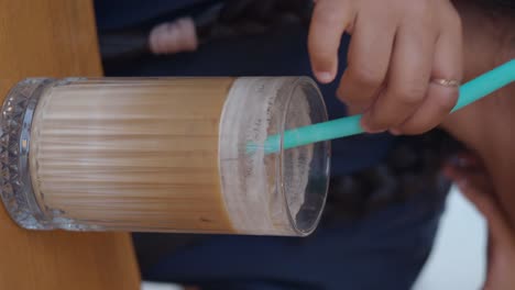 hand stirring an iced latte with a straw